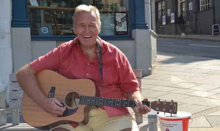 Paul, an older white male, sat outside playing an acoustic guitar